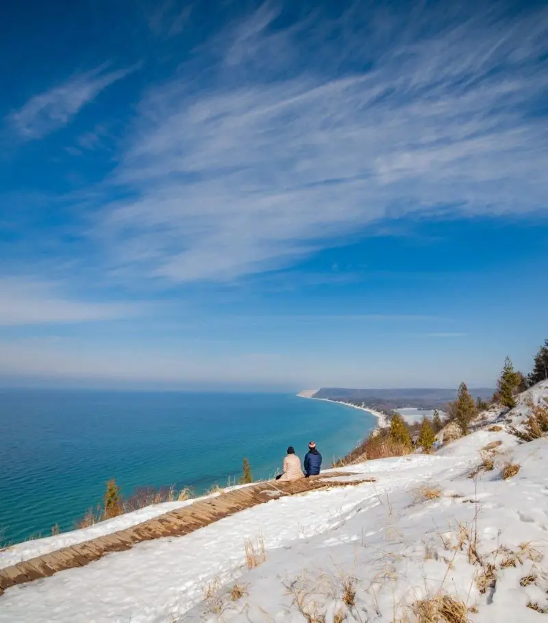 Bright blue water of Lake Michigan and snow-covered Sleeping Bear Dunes NPS. 