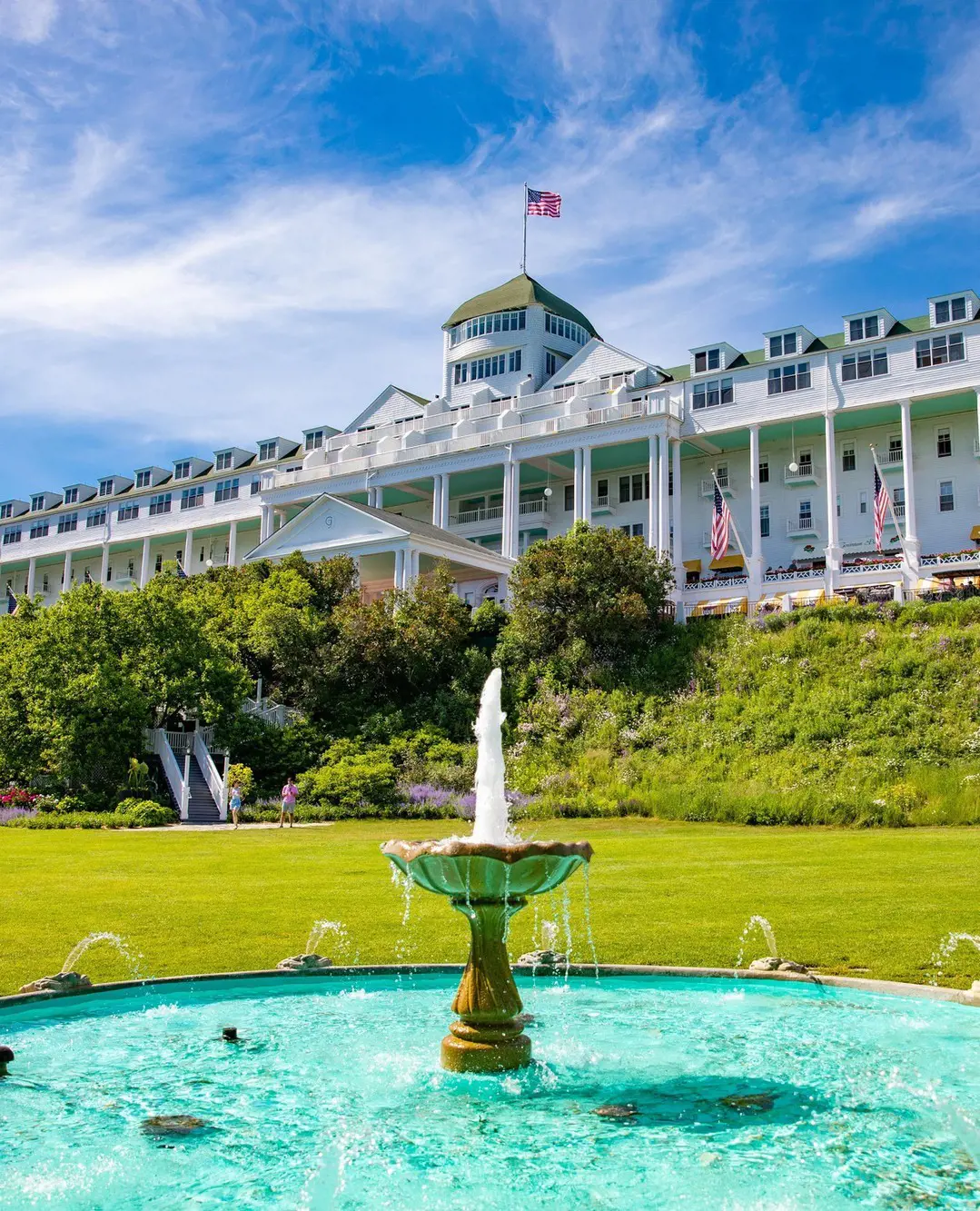 Mackinac Island Grand Hotel with a view of fountain and some greenery, hotel structure in the backdrop. 