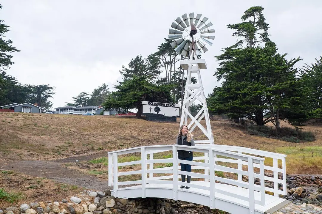 A woman takes a snap standing at the windmill bridge at Oceanpoint Ranch